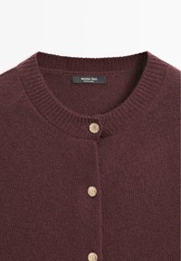 Cardigan in magenta a maglia con scollo rotondo, caratterizzato da tre bottoni color oro e un'etichetta con la scritta "Massimo Dutti." Texture morbida.