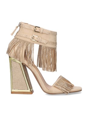 Sandalia beige de tacón alto con tacón block dorado, tiras de ante con flecos decoradas con pequeñas piedras de strass, y cierres de doble hebilla en el tobillo.