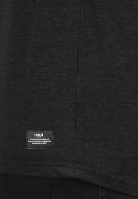 Dark gray t-shirt featuring a soft texture, round neckline, and a fabric label stitched at the lower left side with white text.