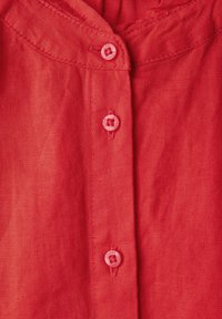 Camicia button-up rossa in lino con una consistenza morbida, colletto curvo e cinque bottoni abbinati sul davanti.