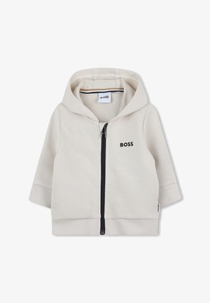 Veste à capuche zippée en mélange de coton beige clair. Elle comporte une fermeture éclair sur le devant, un ourlet côtelé et un logo subtil en noir.