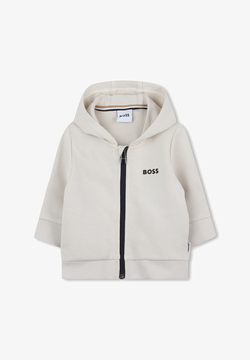Veste à capuche zippée en mélange de coton beige clair. Elle comporte une fermeture éclair sur le devant, un ourlet côtelé et un logo subtil en noir.