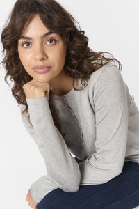 Šedý dlouhý rukáv, kulatý výstřih a detail na knoflík, kombinovaný s tmavě modrými džíny. Měkká textura, ležérní střih.