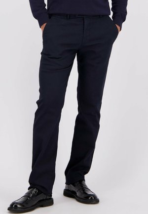 Marineblauwe chino's van een katoenmix, met een klassieke rechte pasvorm, riemlussen en zijzakken; afgewerkt met elegante zwarte schoenen.