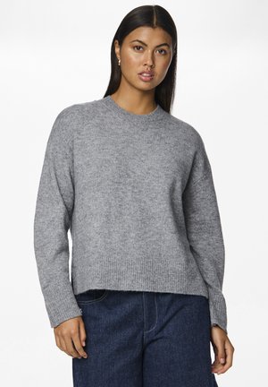 Grå strikket genser med ribbete hals og nederkant, lange ermer og avslappet passform. Myk tekstur, parret med mørke denimbukser.