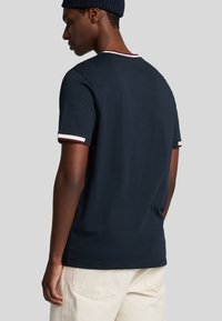 T-shirt a maniche corte di colore blu navy realizzato in cotone, con scollo rotondo e bordi a contrasto, impreziosito da dettagli a righe sui bordi delle maniche.