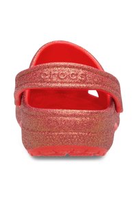 Red glittery clogs with a wide strap at the back, textured footbed, and circular drainage holes. Smooth surface and lightweight design.