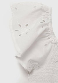 Top bianco in cotone con maniche a balze, caratterizzato da ricami a intaglio e dettagli in elastico smock lungo il corpino.