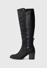 Knee-high black boots with a matte finish and faux leather texture. Block heel and elastic side panels. Decorative emblem near the top.