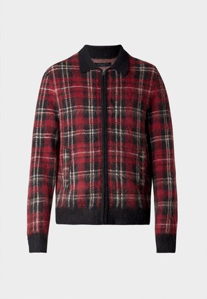 Giacca bomber a quadri rossi e neri, con chiusura a zip, colletto e polsini a coste, e una texture morbida con accenti scuri a contrasto.