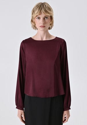 Burgunderfarbene Bluse mit langen Ärmeln und rundem Halsausschnitt, aus glattem Stoff; mit sanft gerafften Ärmeln und einer lockeren Passform an der Taille.