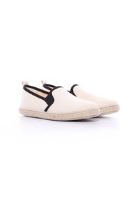 Chaussures slip-on en toile de couleur blanc cassé avec des accents élastiques noirs. Elles possèdent une semelle en jute texturée et un design épuré et minimaliste.