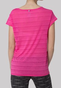 Tričko s krátkým rukávem v jasně růžové barvě s horizontálním pruhovaným vzorem; je vybaveno kulatým výstřihem a jednoduchou visačkou na zadní straně. Měkká, lehká tkanina.