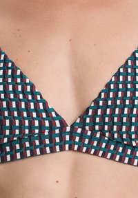 Haut de bikini tissé avec un design en V, avec un motif turquoise, bordeaux, et blanc. Fabriqué en tissu texturé, finition lisse.