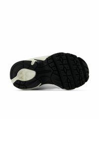 Suola in gomma nera con pattern di presa testurizzati, dotata di un'intersuola bianca e logo New Balance. Il design a punta arrotondata aumenta la flessibilità.