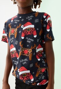 Kurzärmeliges, marineblaues T-Shirt mit einem Gaming-Ferienthema, das Controller, Rentiere und Weihnachtsmannmützen zeigt. Baumwollmaterial, verspielte Drucke.