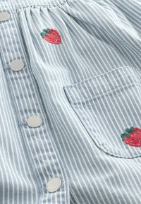 Himmelblau gestreiftes Stoffhemd mit weißen Knöpfen, ausgestattet mit einer Brusttasche und bestickten roten Erdbeeren. Weiche Textur, lässiges Design.
