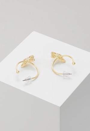 Guldøreringe i form af sommerfugle med klare plastikbagdele, vist på en hvid kasse mod en neutral baggrund.