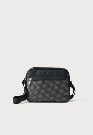 Kompakte Umhängetasche aus schwarz-grau gemustertem Stoff, vordere Reißverschlusstasche, verstellbarer schwarzer Riemen und silberne Reißverschlussanhänger.