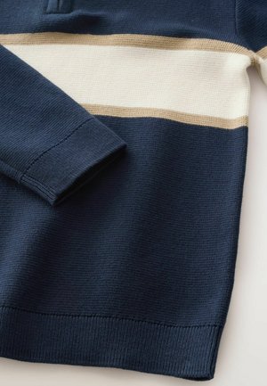 Navy blue sweater with cream and light brown horizontal stripes, featuring a ribbed collar and cuffs, made from a textured knit material.