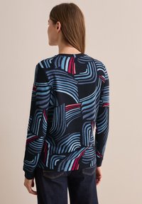 Felpa nera con un audace motivo astratto di linee blu, rosse e bianche. Il tessuto sembra morbido e con texture, con un design a girocollo.