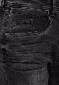 Pantalones vaqueros de mezclilla negra con un diseño clásico de cinco bolsillos, con un ligero desvanecimiento y detalles de costura. Incluye un pequeño bolsillo para monedas y herrajes metálicos.