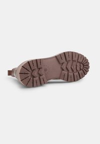 Pruun kummist saapapõhi sügavate mustrite, tekstuuride ja tugevdatud kandega, et tagada haarduvus ja vastupidavus.