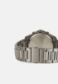 Ανδρικά ρολόγια με ατσάλινο μπρασελέ, γκρι χρώμα, οκταγωνική θήκη και κλείσιμο με κουμπί. Μινιμαλιστικός σχεδιασμός χωρίς ορατούς αριθμούς.