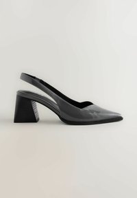 Pilka blizgi slingback avalynė su smailiu pirštu ir masyviu kampiniu kulnu. Lygus paviršius su kontrastinga įdėklu ant kulno.