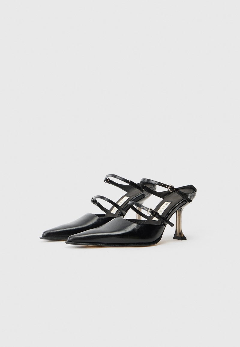 Black leather high-heeled shoes with pointed toe, crisscross straps, and a unique transparent heel design. Smooth texture and minimalist style.