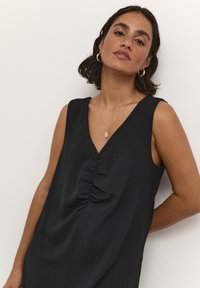 Black sleeveless dress with a V-neckline, featuring gathered detailing at the front. Smooth fabric, relaxed fit, minimalistic design.