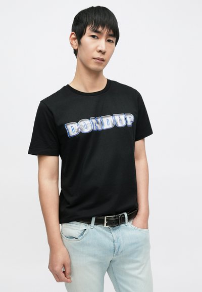 Μαύρο κοντομάνικο μπλουζάκι με μπλε και ασημί γραφικά γράμματα "DONdup", στρογγυλή λαιμόκοψη, σε συνδυασμό με ανοιχτό μπλε τζιν και μαύρη ζώνη.