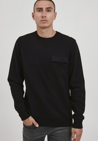 Schwarzes Langarm-Sweatshirt aus Rippstoff, mit einer Fronttasche mit Klappe, rundem Halsausschnitt und engen Bündchen.