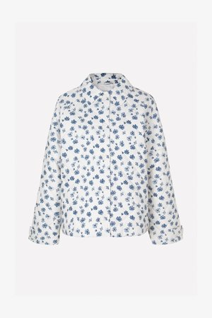 Jachetă matlasată cu fond alb și model floral albastru. Are guler, închidere cu butoane și mâneci scurte cu manșete răsucite.