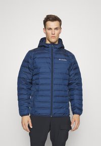 Giacca a vento navy con cappuccio, caratterizzata da pannelli trapuntati orizzontali, cerniera frontale e tasche laterali. Logo sulla parte superiore sinistra del petto.