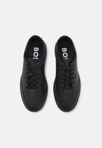Schwarze Leder-Sneaker mit abgerundeter Spitze, flachen schwarzen Schnürsenkeln, eingeprägtem Logo und einer glatten Textur. Designed für die Freizeit.