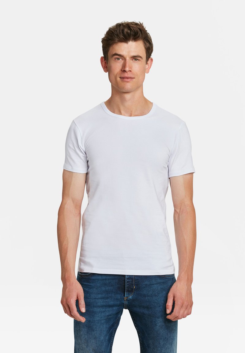 Witte katoenen t-shirt met een klassiek ronde hals en korte mouwen, gecombineerd met blauwe denim jeans, gepresenteerd op een mannelijke model.