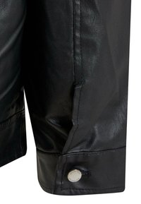 Kurtka skórzana w kolorze czarnym z mankietem, na którym widać przeszycia oraz metalowy zamek błyskawiczny jako ozdobę. Powierzchnia o fakturze z delikatnym połyskiem.