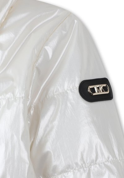 White nylon puffer jacket with a glossy texture. Features black leather patch with a silver logo on the shoulder.
