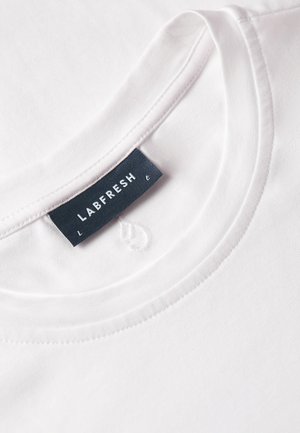 White cotton t-shirt featuring a round neckline. The label, "LABFRESH," is stitched in dark blue on the inner neckline. Smooth texture.
