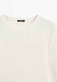Cremefarbenes Langarmshirt mit rundem Ausschnitt und Massimo Dutti-Etikett am inneren Kragen, präsentiert auf weißem Hintergrund.
