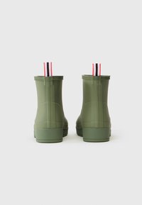 Stivali alla caviglia in gomma verde con una finitura testurizzata, caratterizzati da un design alto e da linguette rosse, bianche e nere a strisce sul retro.