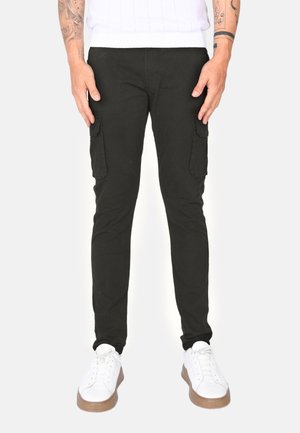 Pantaloni cargo neri con tasche laterali, dal design slim fit, realizzati in un tessuto misto cotone. Abbinati a sneaker bianche. Stile minimalista.