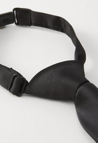 Gravata de satin preta com acabamento texturizado, faixa ajustável e uma forma clássica apresentando um design de nó tradicional.