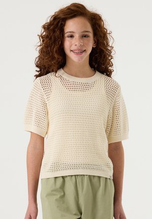 Gebreide trui met korte mouwen in roomkleur, met een mesh ontwerp, voorzien van een ronde hals en geribbelde boorden, gedragen over lichtgroene broek.