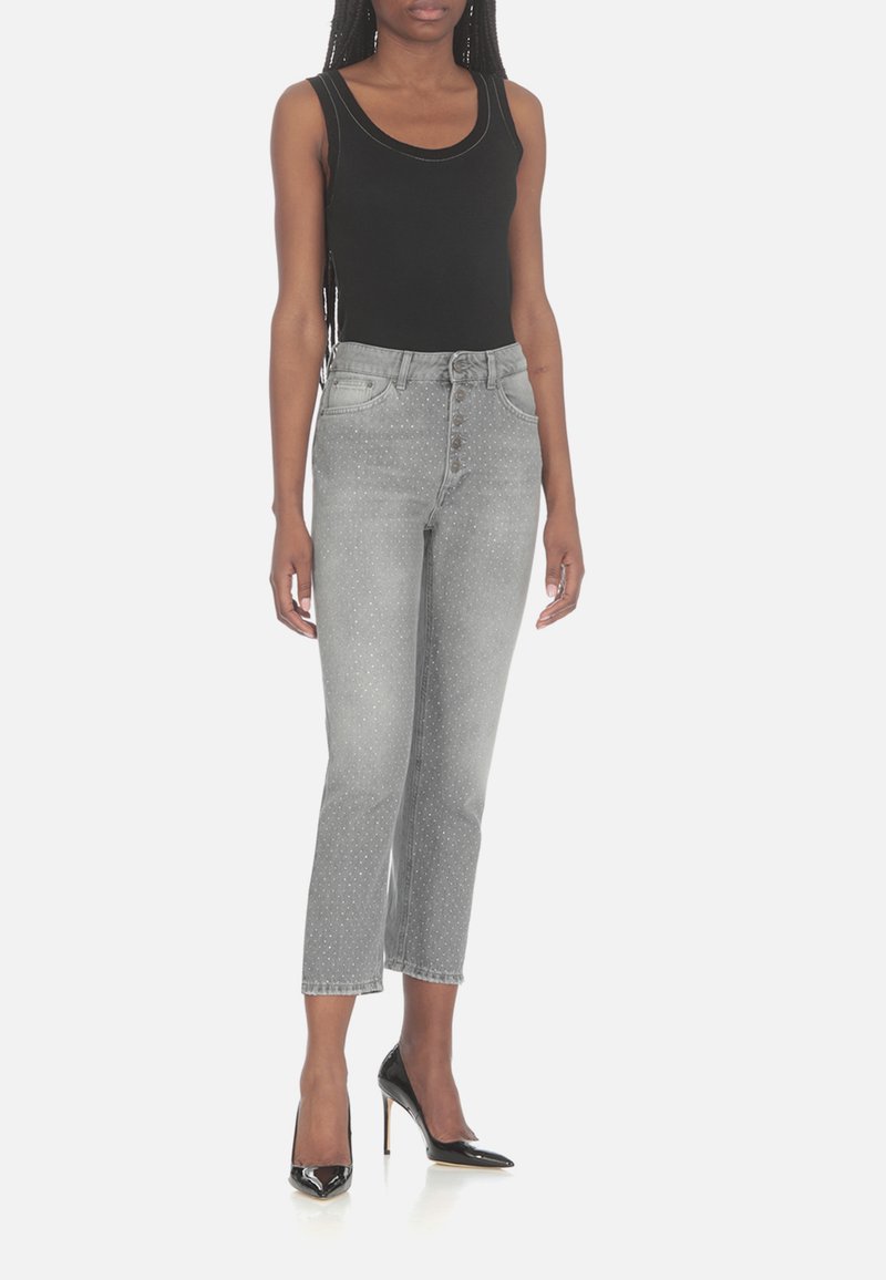 Top nero abbinato a jeans a vita alta grigi a pois, con chiusura a bottoni e gambe corte, completato da tacchi alti neri.