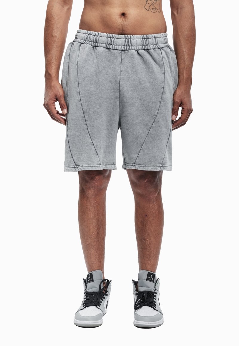 Pantalones cortos de mezcla de algodón gris con cintura elástica, costuras frontales y un ajuste relajado, combinados con zapatillas altas en negro y blanco.