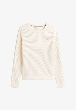 Kreemikas korvhemmaga palmikutest kampsun, pikkade varrukatega, ümmarguse kaelusega ja väikese punase, valge ja sinise ristküliku kujulise logoga vasakul rinnal.