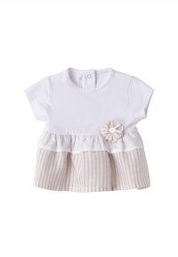 Top de algodón blanco con mangas cortas, que presenta un peplum de capas en tela a rayas de color beige y un acento decorativo de flor. Cierre de botón en la parte posterior.