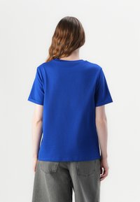 Royal blue bawełniany t-shirt z okrągłym dekoltem i krótkimi rękawami, charakteryzujący się gładką teksturą i luźnym krojem, widok z tyłu.